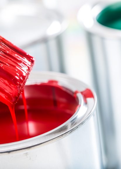 Close-up brush with red color over paint can.